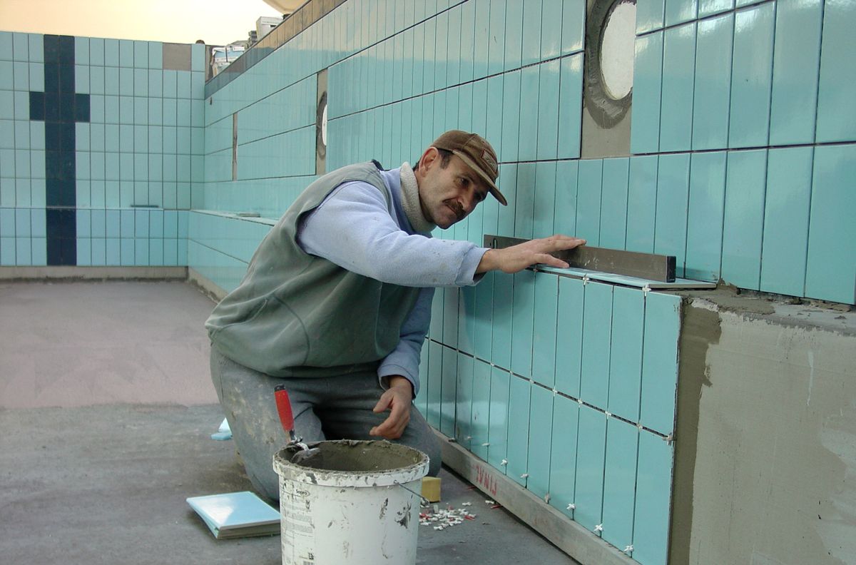 Sfeerbeeld van een vakman die tegels op de wand zet